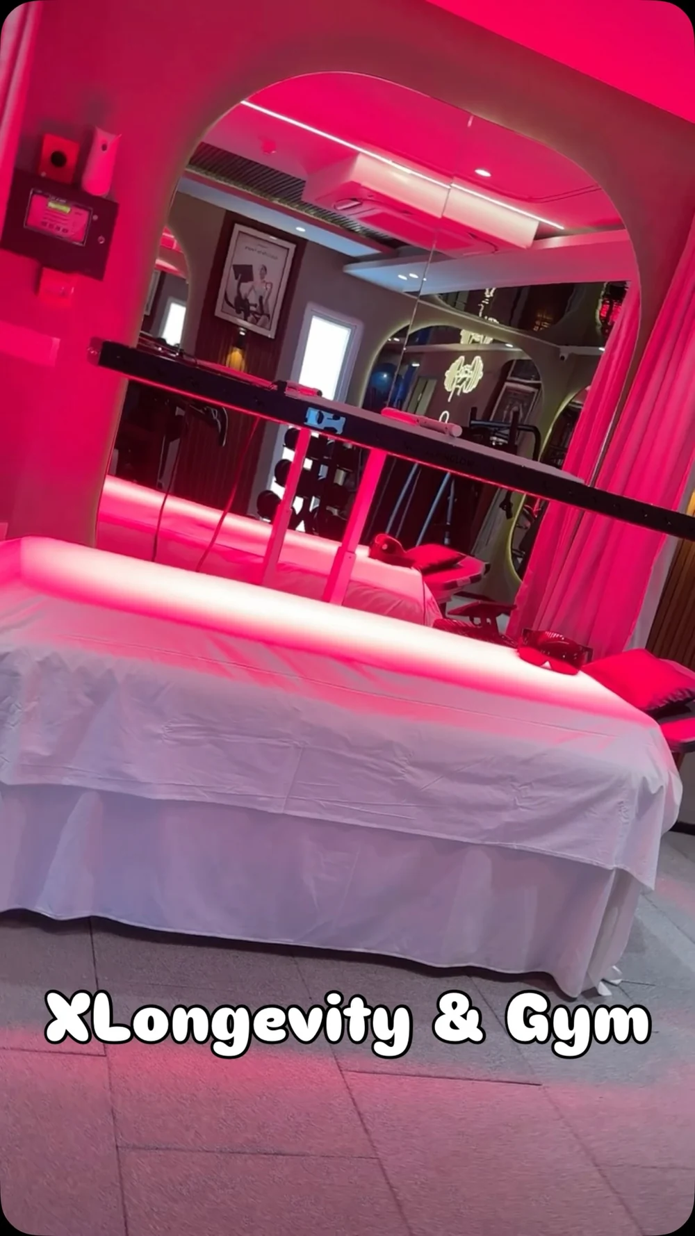 Original gym tour reel cover showing the red-light treatment bay with curtains, bed, and arched mirror.